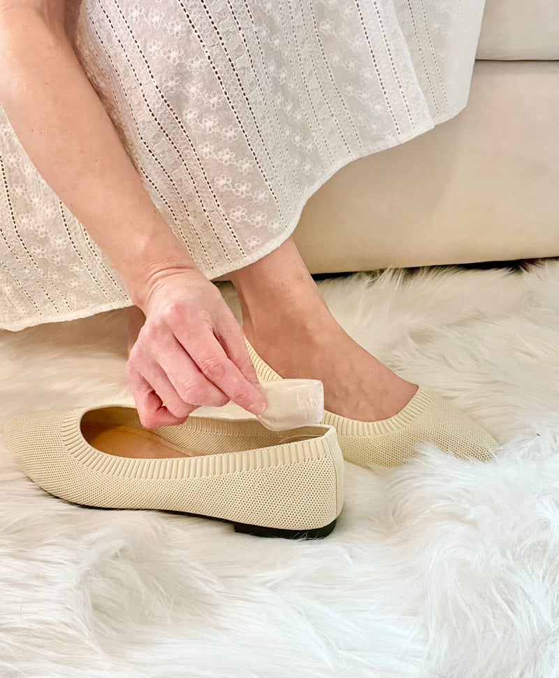 Woman placing Foot Petals gel back of heel cushions into flat shoe