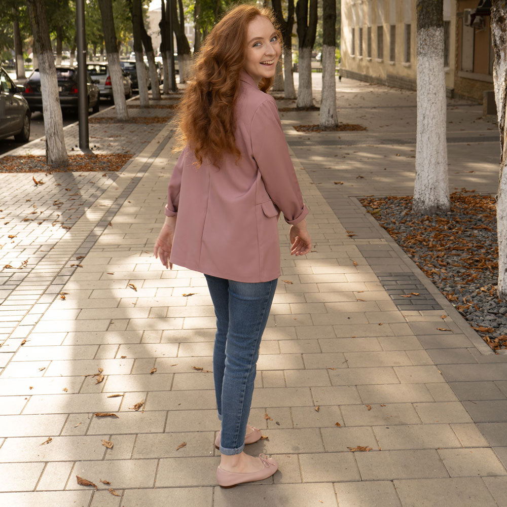 Girl walking down sidewalk while wearing pink flats that have Foot Petals 2-in-1 Ball of Foot and Arch Support cushions inside.