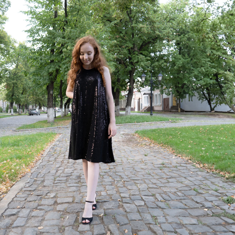 Woman wearing black sequins dress walking down stone sidewalk while wearing black high heels with Foot Petals 3/4 Insert Cushions inside