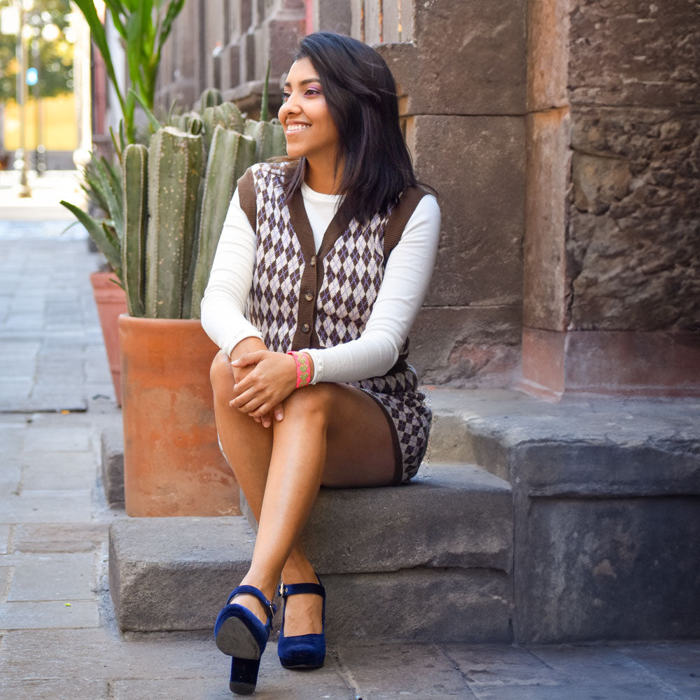 Woman sitting on stone stairs while wearing dark blue velvet high heels with Foot Petals Back of Heel Cushions inside #color_assorted-3-pairs