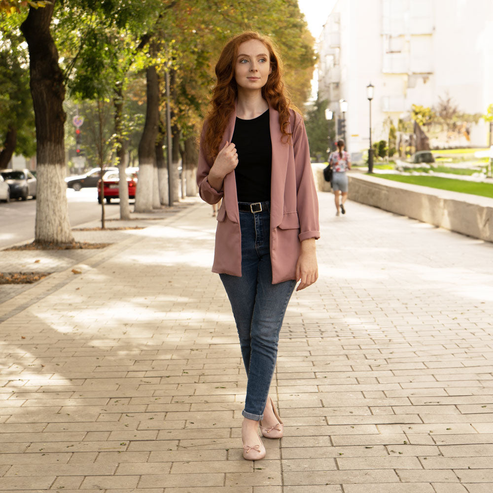 Woman walking down brick-style concrete sidewalk while wearing pink flats with Foot Petals Ball of Foot Cushions inside #options_clear-3-pairs