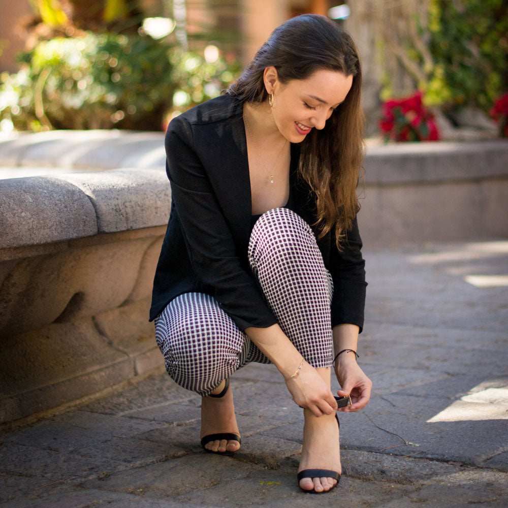 Woman kneeling to adjust high heel shoe strap with Foot Petals 3/4 Insert cushions inside #color_black